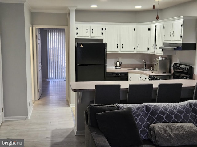 kitchen with a sink, black appliances, light countertops, under cabinet range hood, and open floor plan