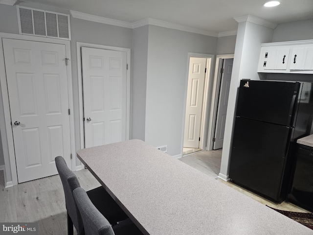 kitchen with crown molding, light wood finished floors, visible vents, and freestanding refrigerator