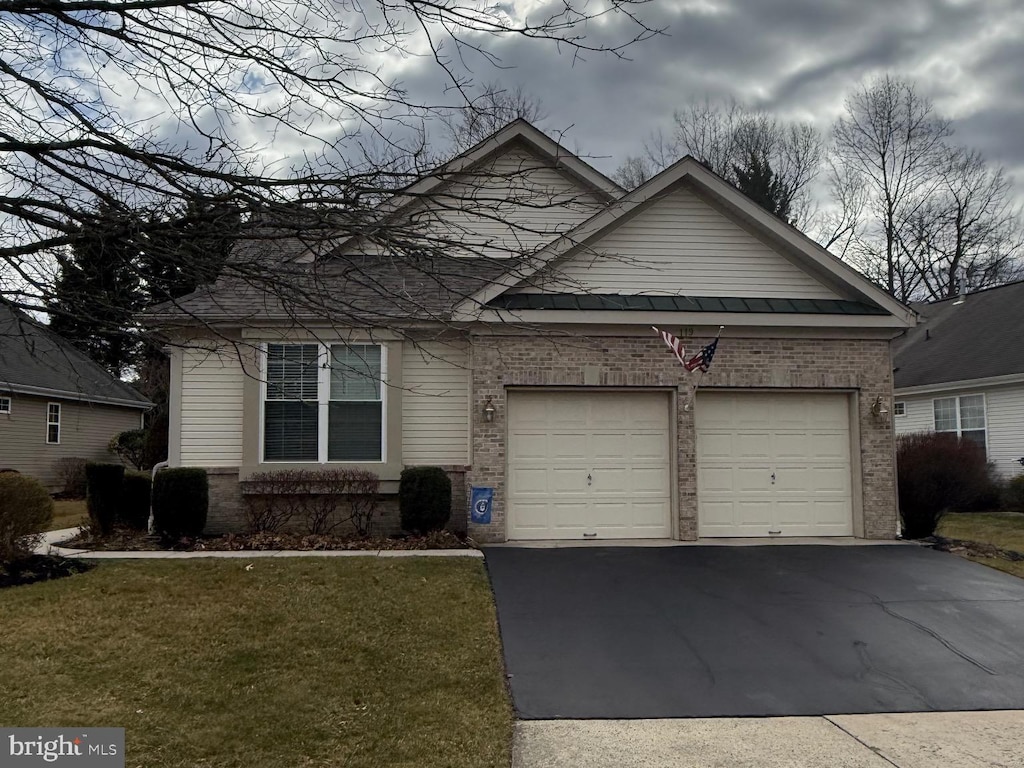 view of front of house featuring a front lawn, an attached garage, brick siding, and driveway