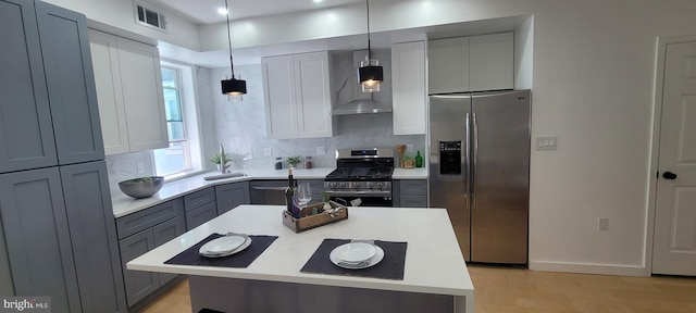 kitchen with gray cabinetry, stainless steel appliances, visible vents, light countertops, and wall chimney range hood