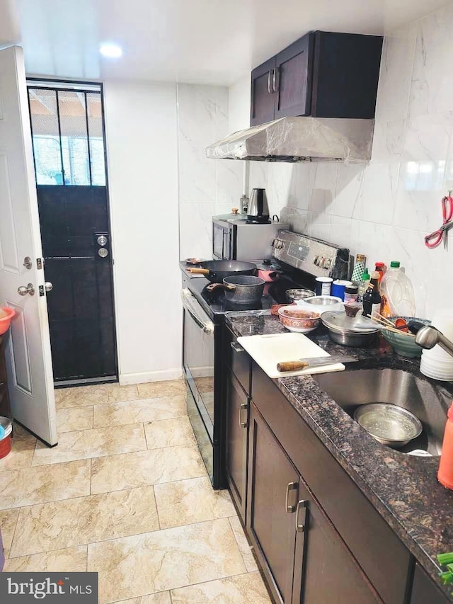 kitchen featuring range with electric stovetop, backsplash, a sink, dark stone counters, and under cabinet range hood