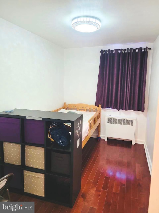 bedroom with radiator and dark wood finished floors