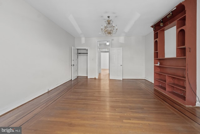 spare room featuring baseboards, a chandelier, and wood finished floors