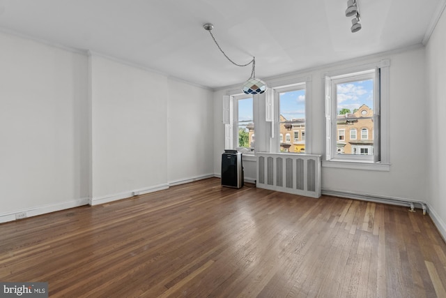 interior space featuring hardwood / wood-style flooring, track lighting, baseboards, and crown molding