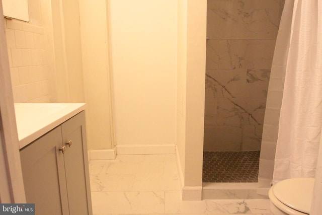 bathroom with toilet, vanity, baseboards, marble finish floor, and a tile shower