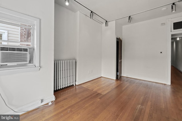 empty room with radiator heating unit, wood-type flooring, and baseboards