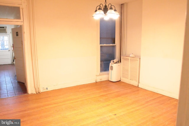 spare room with baseboards, wood finished floors, and a notable chandelier