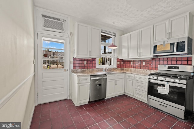 kitchen with stainless steel appliances, tasteful backsplash, a sink, and white cabinets