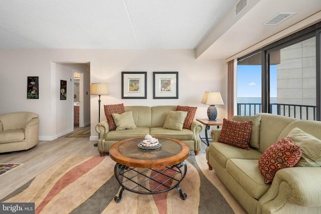 living room featuring visible vents, baseboards, and wood finished floors