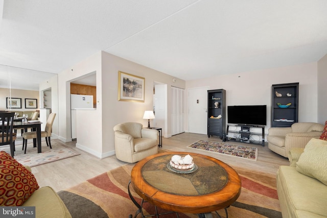 living area with light wood-style flooring and baseboards