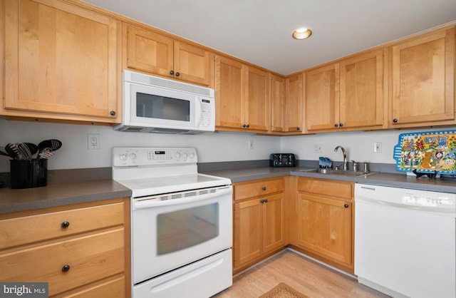 kitchen featuring light wood-type flooring, dark countertops, white appliances, and a sink