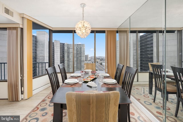 dining space with floor to ceiling windows, a city view, visible vents, an inviting chandelier, and light wood-type flooring