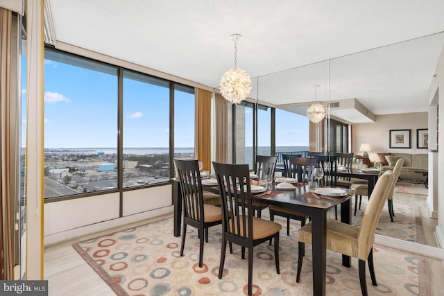 dining space featuring a chandelier, light wood-style flooring, plenty of natural light, and visible vents