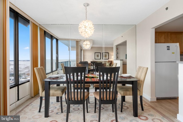 dining area featuring a chandelier, light wood finished floors, and a wall of windows