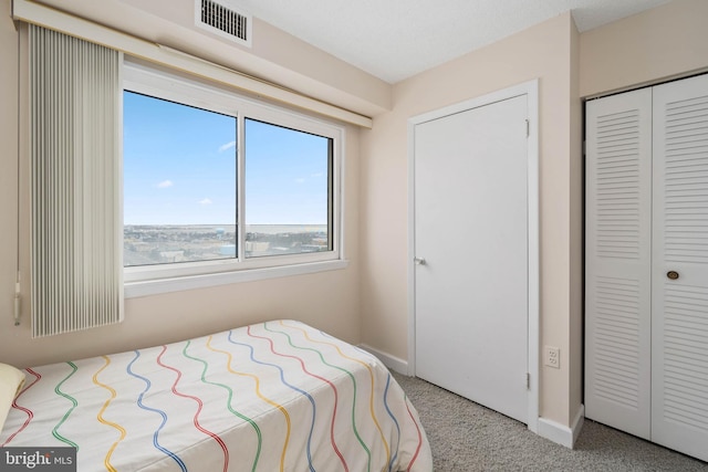 bedroom with carpet floors, a closet, visible vents, and baseboards