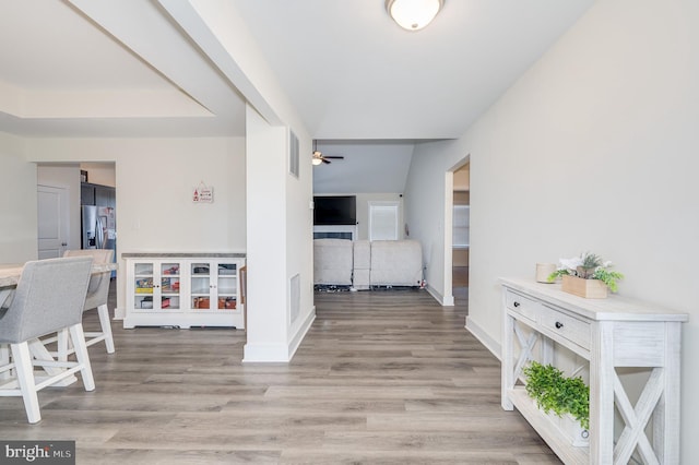 corridor with light wood-style flooring, visible vents, and baseboards