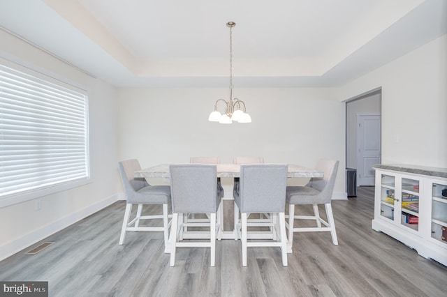 dining area featuring visible vents, a raised ceiling, a notable chandelier, and baseboards