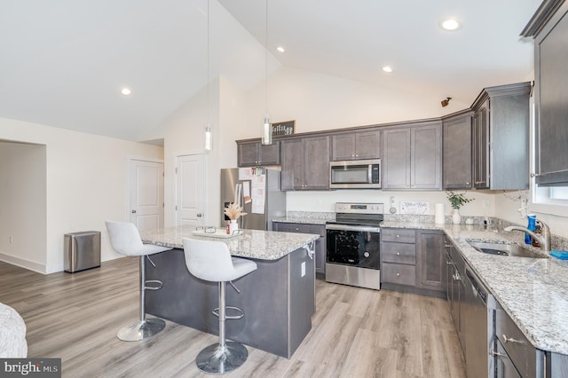 kitchen featuring appliances with stainless steel finishes, a kitchen island, light wood-style floors, and a sink