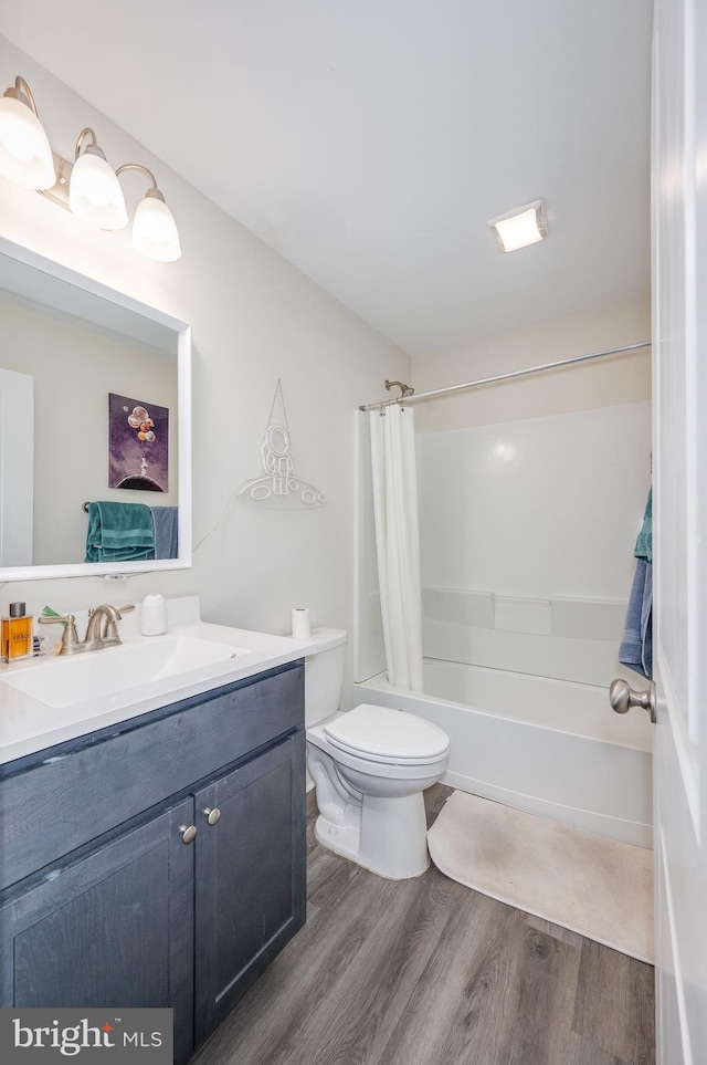 bathroom with shower / bath combo with shower curtain, toilet, wood finished floors, and vanity