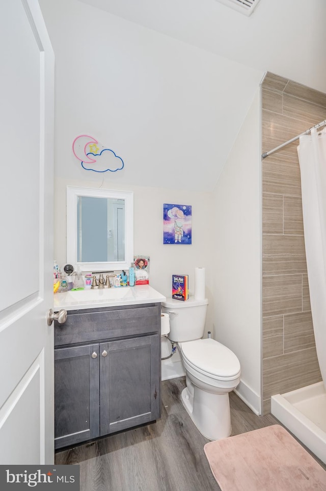 full bathroom featuring toilet, a stall shower, wood finished floors, vanity, and vaulted ceiling