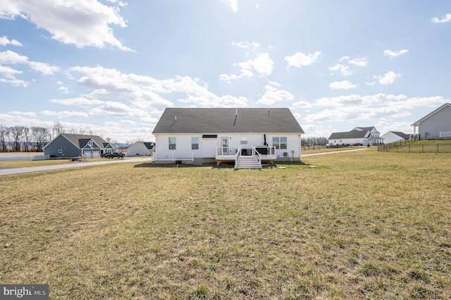 rear view of property with a lawn, a wooden deck, and fence