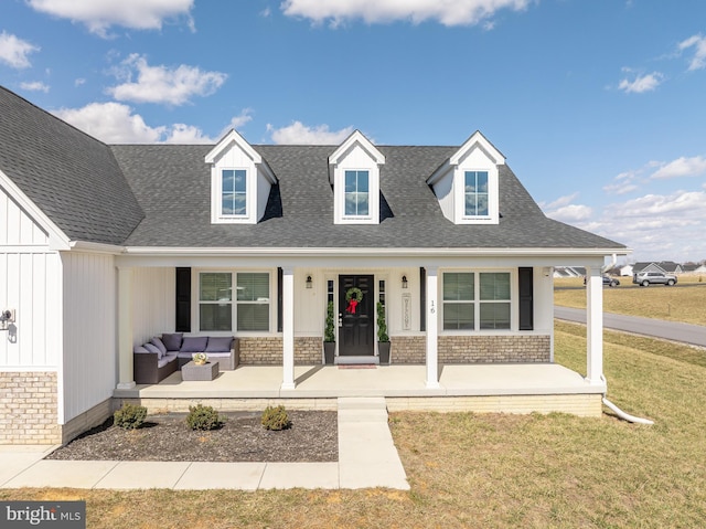 view of front of property with brick siding, a porch, a front yard, and roof with shingles