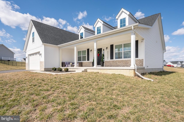 view of front of home with a front lawn, brick siding, covered porch, and driveway