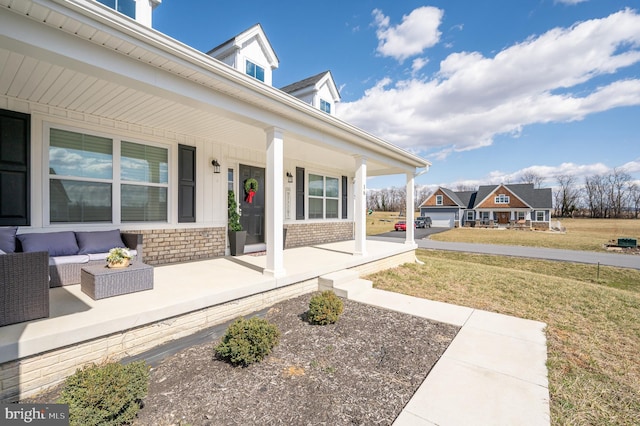 view of exterior entry featuring brick siding, an outdoor living space, a lawn, and covered porch