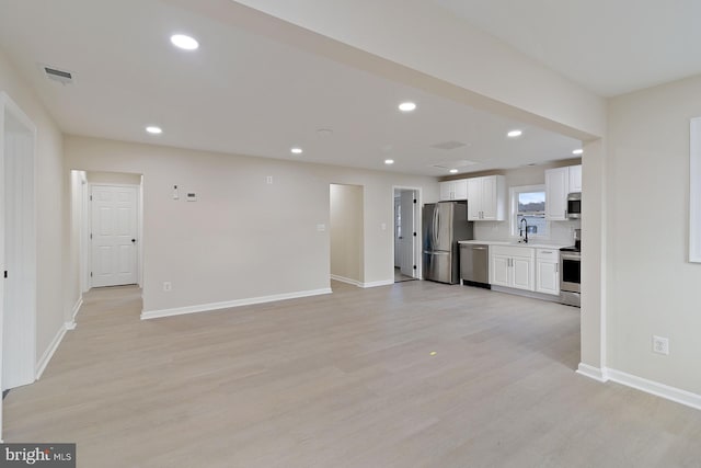 unfurnished living room with visible vents, baseboards, light wood-style flooring, a sink, and recessed lighting