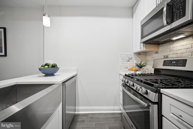 kitchen featuring tasteful backsplash, baseboards, light stone countertops, white cabinets, and stainless steel appliances