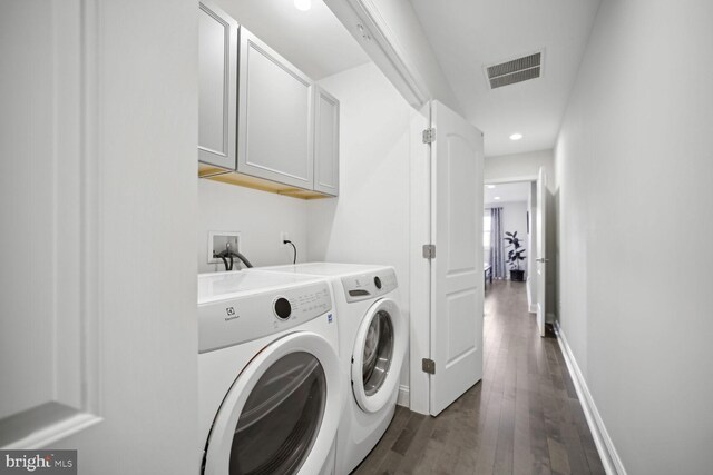 washroom featuring visible vents, dark wood-type flooring, baseboards, washer and clothes dryer, and cabinet space