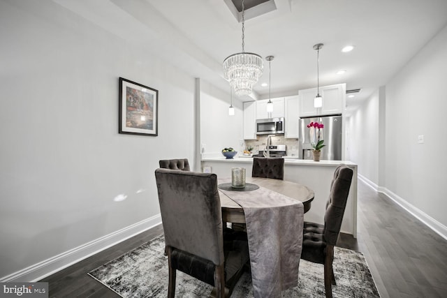 dining room with dark wood finished floors, a notable chandelier, recessed lighting, and baseboards