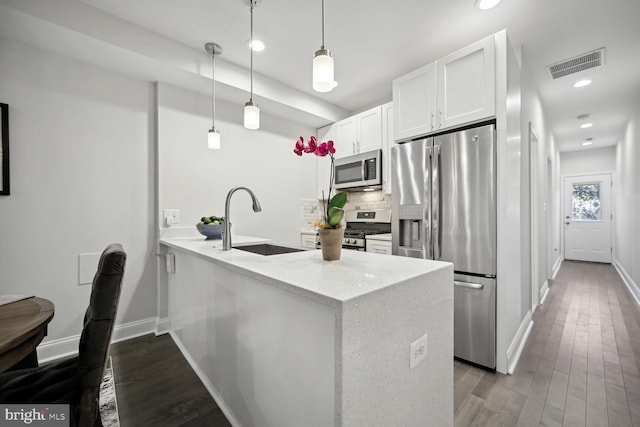 kitchen featuring visible vents, a sink, tasteful backsplash, stainless steel appliances, and a peninsula