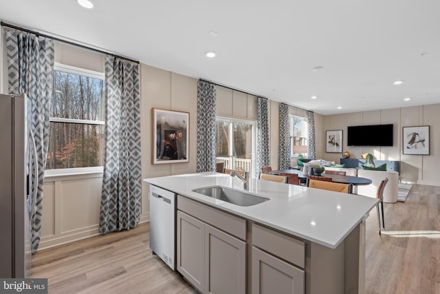 kitchen featuring light wood-style flooring, appliances with stainless steel finishes, light countertops, and a sink