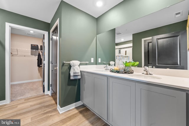 full bathroom featuring a walk in closet, visible vents, a sink, and wood finished floors