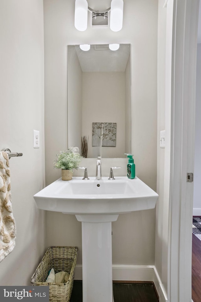 bathroom featuring wood finished floors, baseboards, and a sink