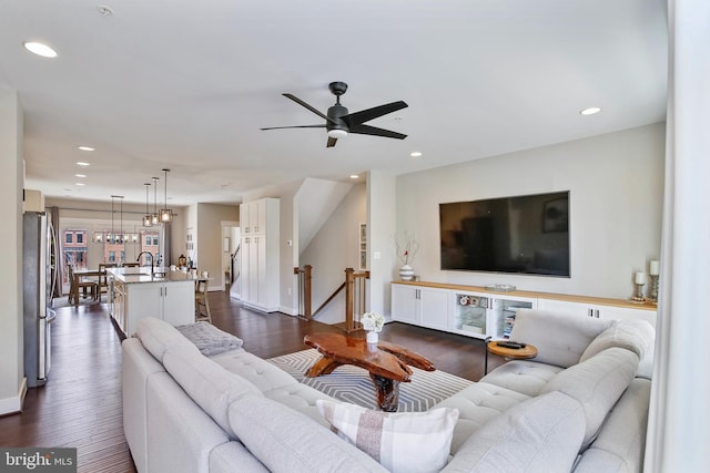 living area with recessed lighting, baseboards, dark wood finished floors, and ceiling fan with notable chandelier