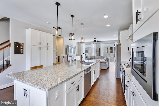 kitchen featuring open floor plan, stainless steel appliances, dark wood-style flooring, and a sink