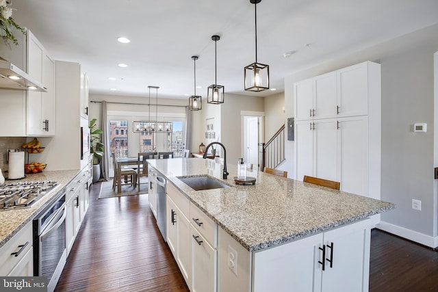 kitchen with an island with sink, stainless steel appliances, dark wood-style floors, white cabinetry, and a sink