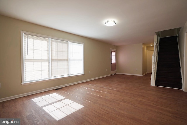 unfurnished room with stairway, wood finished floors, visible vents, and baseboards