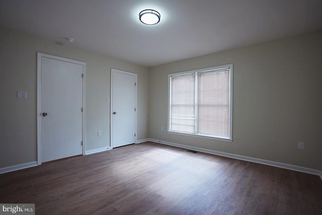 unfurnished bedroom featuring baseboards, visible vents, and wood finished floors