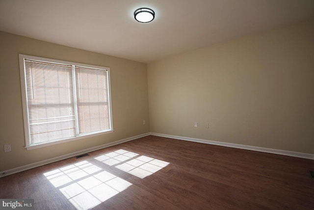 unfurnished room featuring visible vents, baseboards, and wood finished floors