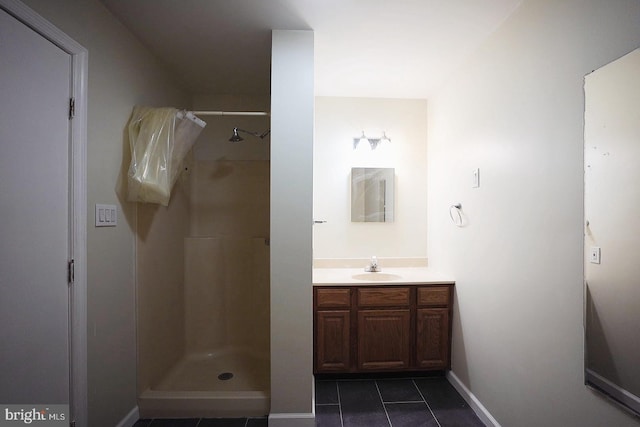 full bathroom featuring a stall shower, tile patterned floors, baseboards, and vanity