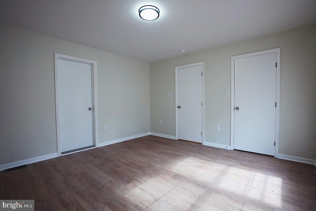 unfurnished bedroom featuring wood finished floors, visible vents, and baseboards