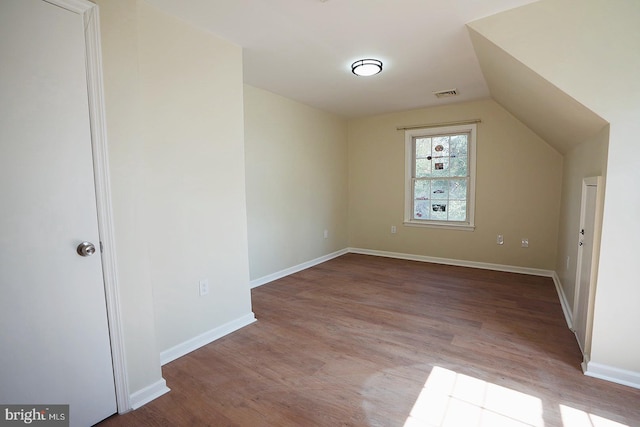 bonus room featuring lofted ceiling, visible vents, baseboards, and wood finished floors