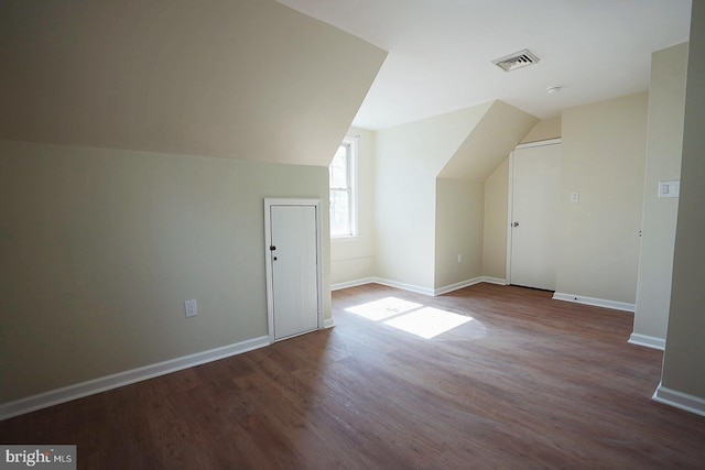 additional living space featuring baseboards, visible vents, vaulted ceiling, and wood finished floors