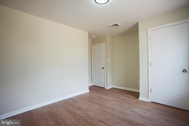 unfurnished bedroom with wood finished floors, visible vents, and baseboards