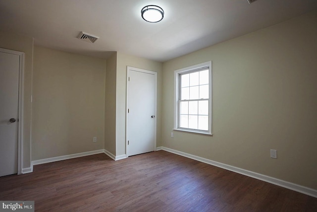 unfurnished bedroom featuring a closet, wood finished floors, visible vents, and baseboards