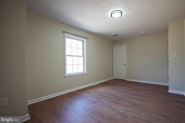 spare room with visible vents, baseboards, and wood finished floors