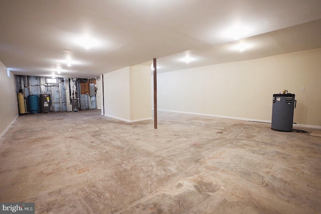 finished basement with heating unit, water heater, baseboards, and electric water heater